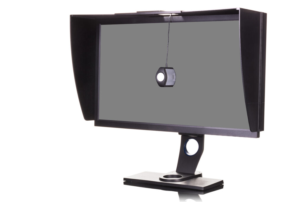 Profesionální fotografický monitor se stínícím krytem a kalibrátorem izolovaný na bílém pozadí s ořezovou cestou